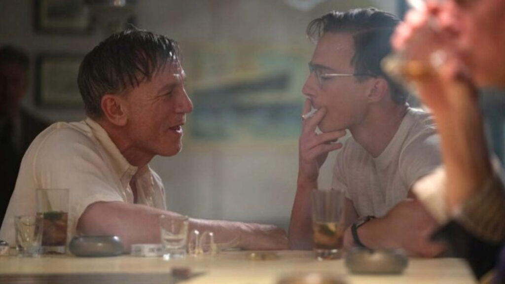 Daniel Craig and Drew Starkey looking at each other in Queer