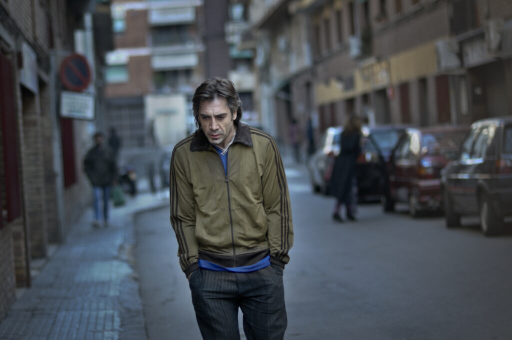 Javier Bardem as Uxbal in Biutiful walking alone down a street, his face etched with sorrow and exhaustion